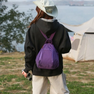 Détail du sac à dos violet à carreaux avec fermeture éclair sur un modèle de camping