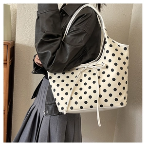 Detailed close-up of a cream nylon tote bag with black polka dots and a cute bow tie