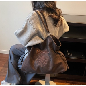 Close-up of brown suede tote bag featuring embroidered sunflower and Maodi lettering