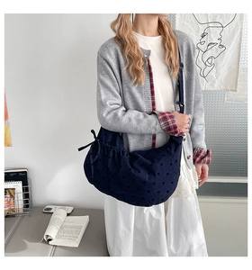 Détail du sac croissant en velours côtelé bleu marine avec pois et nœud décoratif