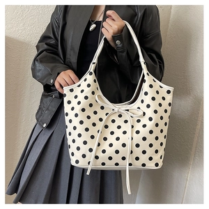 Detailed view of polka dot tote bag with a white bow drawstring on shoulder