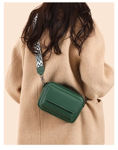 Detalle de bolso bandolera de cuero verde con correa tejida mostrado en una modelo