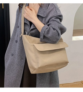 Detail of khaki nylon crossbody bag featuring a large flap pocket and wide strap on a model