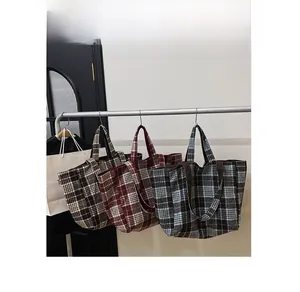 Vue détaillée de trois sacs cabas en laine à carreaux marron, rouge et bleu sur support