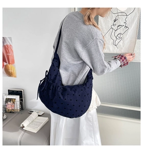Détail d'un sac à bandoulière bleu marine à pois avec nœud décoratif sur le côté