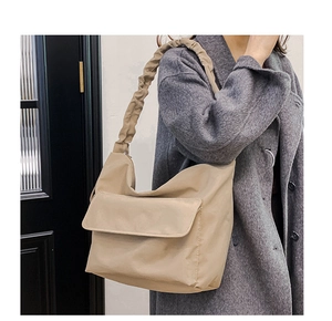 Detail of beige nylon shoulder bag with pleated handle and front pocket for commute