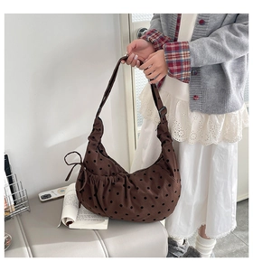 Détail d'un sac hobo marron à pois avec un nœud latéral et sangle réglable