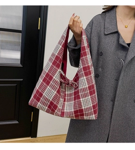 Close-up of red and white plaid tote bag made of textured tweed on dark coat