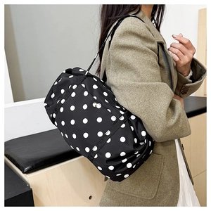 Sac fourre-tout noir à pois blancs porté à l'épaule avec détail de boucle métallique
