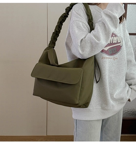 Detail of olive green nylon bag featuring ruched strap and front flap pocket on a model