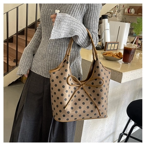 Detail shot of the faux leather bow on a coffee brown polka dot nylon tote bag