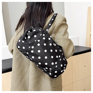 Détail du sac à bandoulière léger à pois noirs et blancs porté sur l'épaule