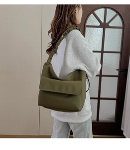 Detail of olive green nylon bag showing the pleated cloud shoulder strap and front flap pocket