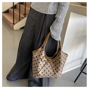 Detailed view of khaki nylon tote bag featuring black polka dots and brown leather handles