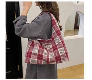 Detail of red and white plaid tote bag featuring a decorative side bow on thick fabric