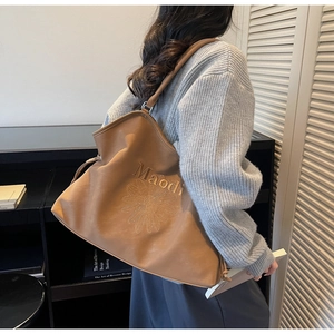 Close-up of caramel PU leather tote bag featuring daisy and letter embroidery detail