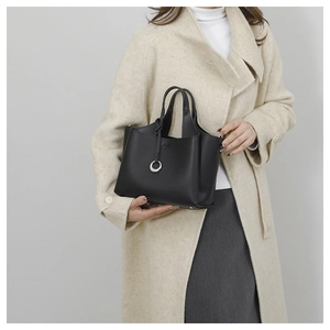 Détail d'un sac seau noir en cuir grainé avec breloque métallique et double poignée