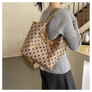 Detail view of large tote bag with black polka dots and oversized decorative bow