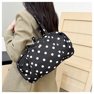 Vue détaillée du sac à bandoulière noir à pois blancs porté sur un blazer kaki chic