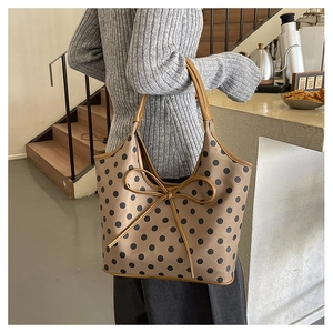 Detail view of large brown polka dot tote bag with leather bow and shoulder straps