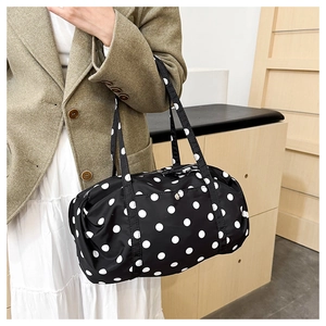 Gros plan du sac de voyage léger à pois noirs et blancs avec deux poignées de transport