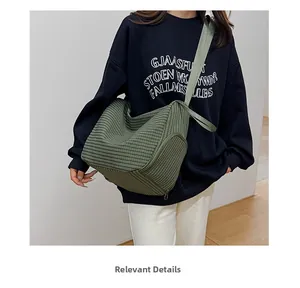 Detail of green corduroy crossbody bag texture and zipper closure worn by a model