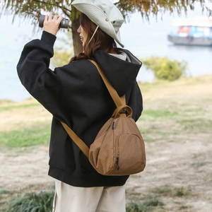 Sac à dos léger à carreaux marron porté par un mannequin dans un décor naturel extérieur