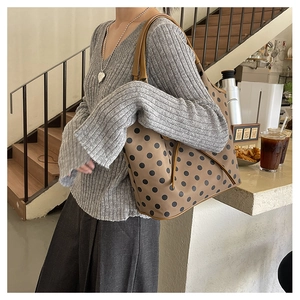 Detailed view of a brown tote bag with black polka dots styled with a grey sweater