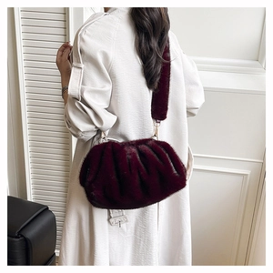 Détail du sac nuage en peluche bordeaux plissé porté par un mannequin en manteau blanc