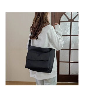 Rear view of model wearing a large black nylon crossbody messenger bag for daily commute