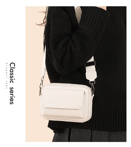 Bolso bandolera de cuero blanco con elegante correa de jacquard llevado por una modelo