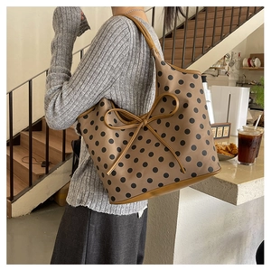 French style brown polka dot tote bag with large bow detail shown on a female model