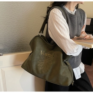 Close-up of olive green tote bag featuring elegant embossed floral patterns and lettering