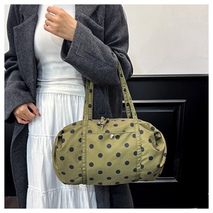 Sac à bandoulière à pois tenu par un mannequin pour le voyage et le sport
