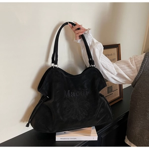 Detail of black suede tote bag featuring Malodi embroidery and chic drawstring closure