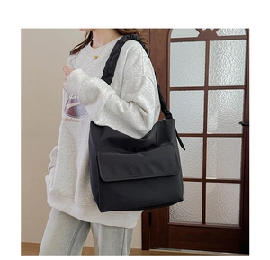 Detail of minimalist black nylon shoulder bag with flap pocket and pleated strap style