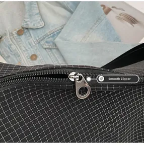 Close-up of smooth silver metal zipper on minimalist black and white checkered bag