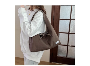 Detailed shot of brown canvas tote bag featuring fashion label and black white plaid bow