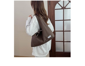Detail view of a vintage dark brown canvas tote bag with a white fashion label and woven strap