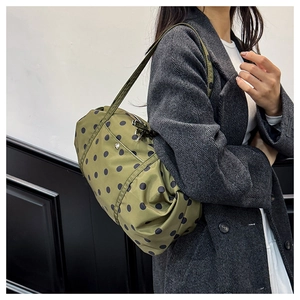 Sac bandoulière vert olive à pois noirs porté par un mannequin en manteau de laine gris