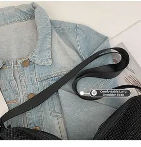 Detail of wide nylon shoulder strap on black checkered hobo bag with zip closure