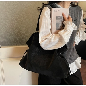 Detail of black tote bag featuring embossed floral pattern and M letter on leather surface
