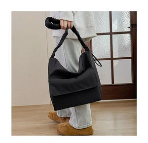 Detail of minimalist black nylon shoulder bag with ruffled scrunchie handle and front pocket