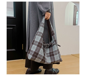 Detail of vintage plaid tote bag featuring a bow tie ornament and textured fabric
