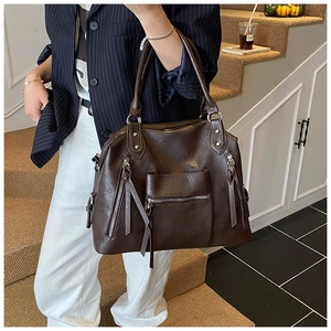 Detail view of large dark brown PU leather tote with silver hardware and tassels