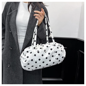 Sac cylindrique à pois porté sur un manteau en laine grise montrant les détails du tissu