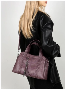 Detail of purple leather tote bag showing woven texture, fringe tassel and crossbody strap