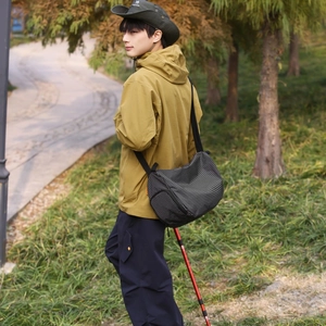 Détail d'un sac bandoulière à carreaux porté avec une veste d'extérieur verte