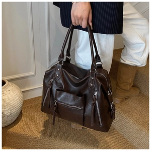 Detail of dark brown PU leather Boston bag with zipper pockets and tassel accents