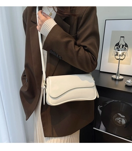 Chic white crossbody bag with asymmetric flap worn by model in professional suit
